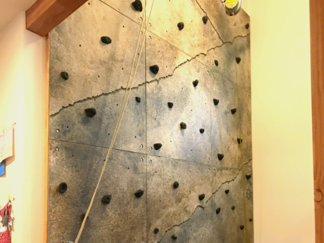 A view of a multi-story climbing wall in a home entryway, including ropes and rope organization