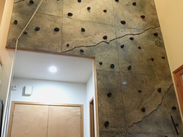 A multi-story climbing wall installed in a home's foyer is mounted around and above access to storage and other rooms.